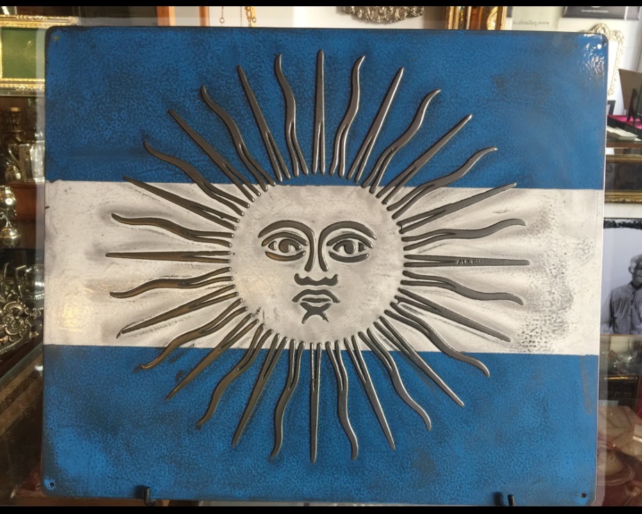 Vista frontal completa de la placa de la bandera argentina con el Sol de Mayo en relieve