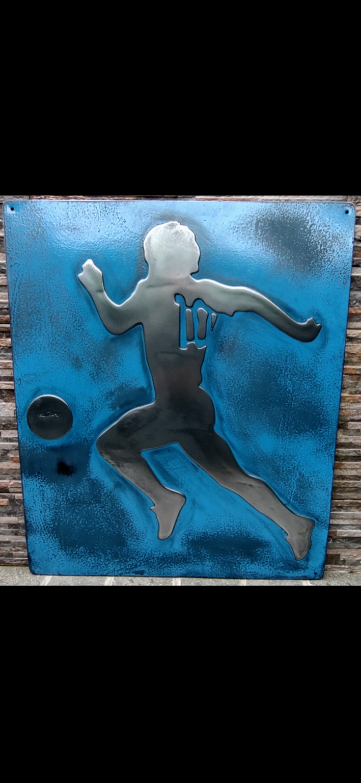 Vista frontal completa de la placa azul de hierro vintage con la silueta de un futbolista en relieve