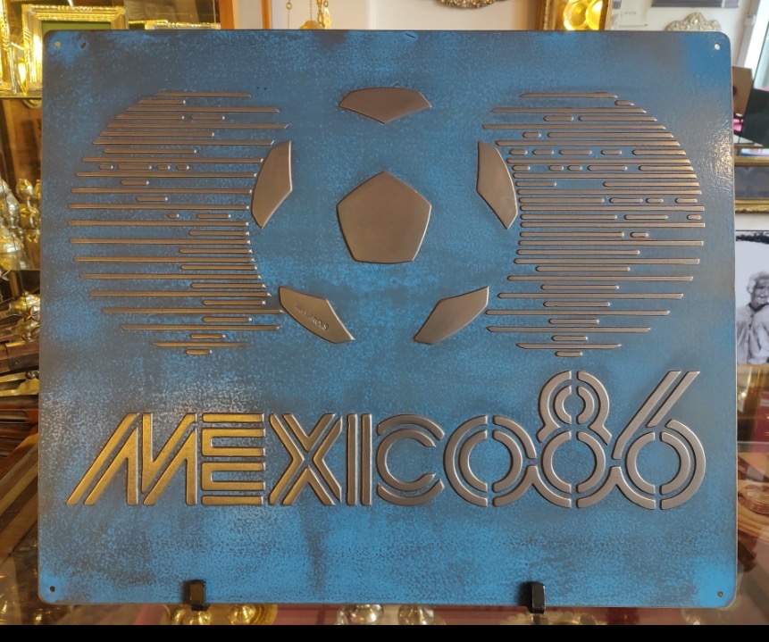 Vista frontal completa de la placa azul México 86 de hierro vintage con letras de fútbol en relieve